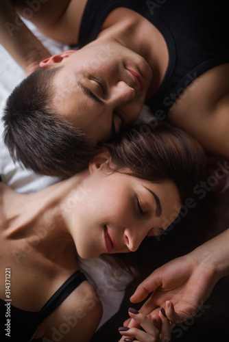 Top view of couple in love. Close-up portrait of the Lovers who lie on the bed at home, head to head. The morning of the newlyweds, tenderly resting on festive day off at home. Concept of tactility
