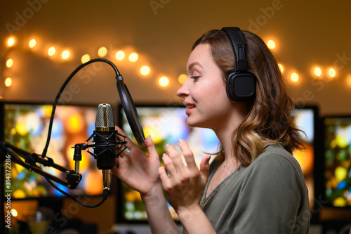 Girl blogger or radio host, working with a microphone, reading podcasts or news on the air. Homely and cozy atmosphere, work at home photo