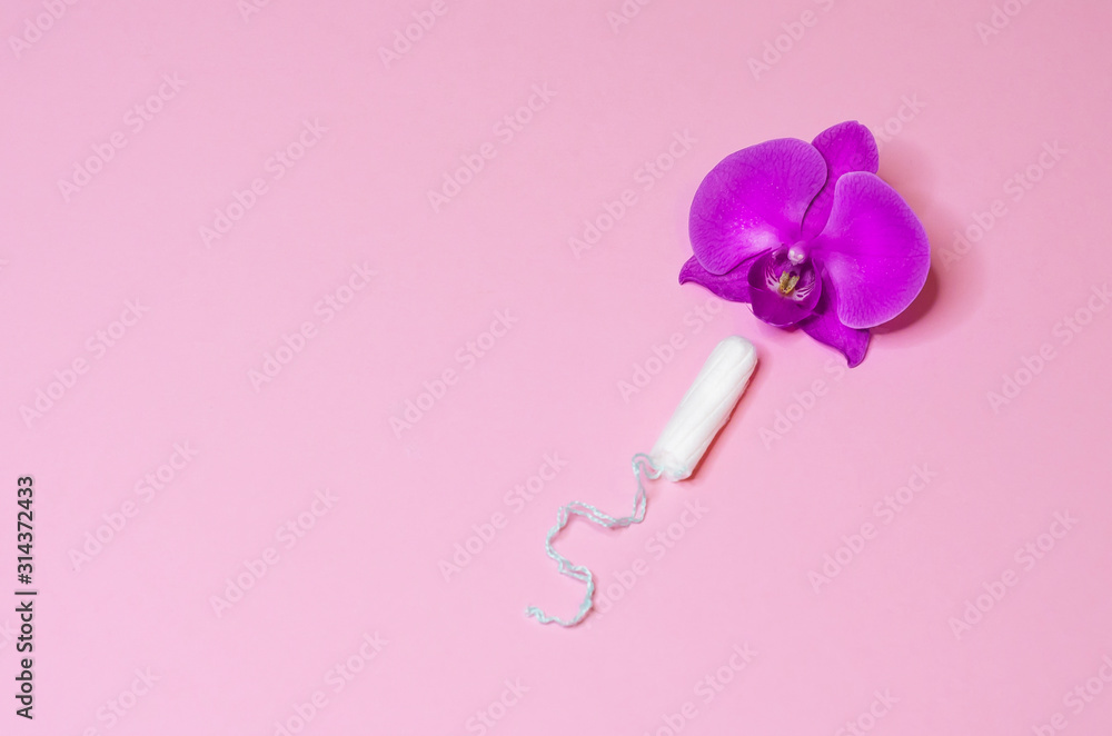 tampon as a remedy for critical menstrual days with flower orchid on pink background. hygiene, care and cleanliness of woman. copy space for text