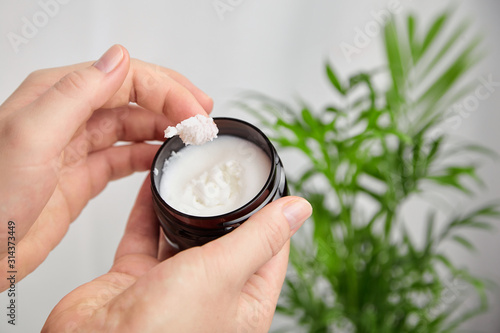 Shea butter in jar, cosmetic skin treatment product. Woman applying moisturizer to her skin of hand photo