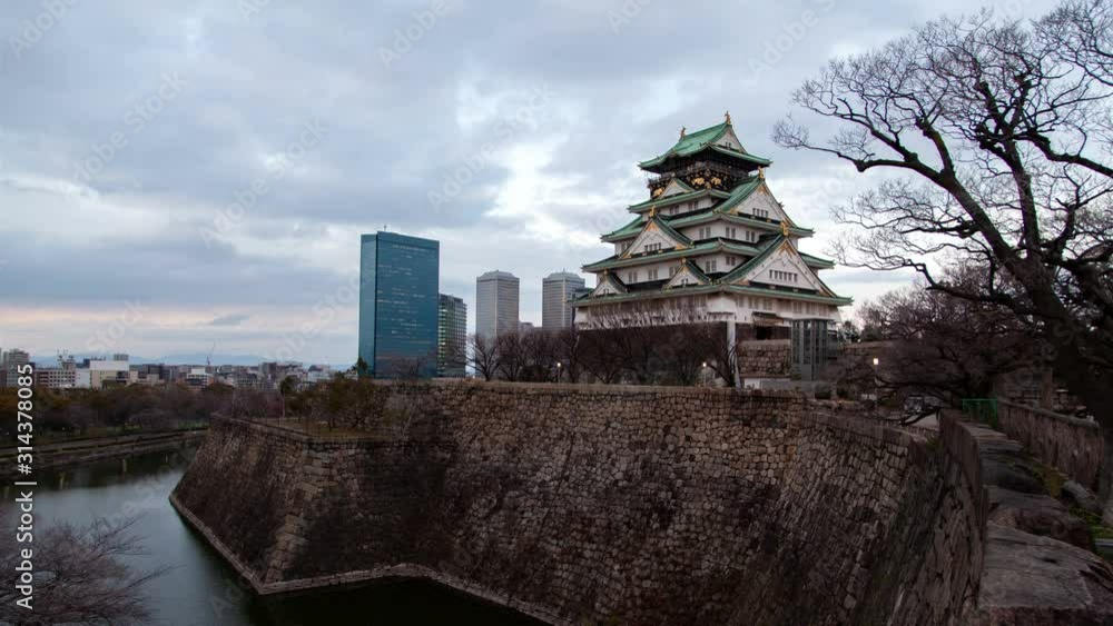 Timelapse Osaka ancient castle with museum and fortress with defence wall against skyscrapers from sunset till night illumination