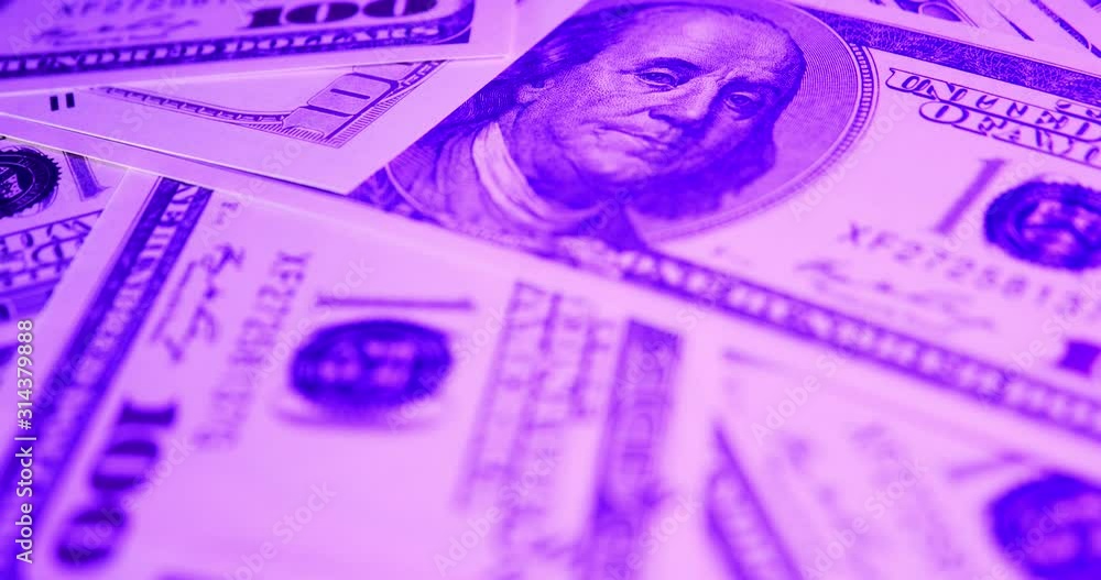 A pile of one hundred US banknotes with RGB colors light