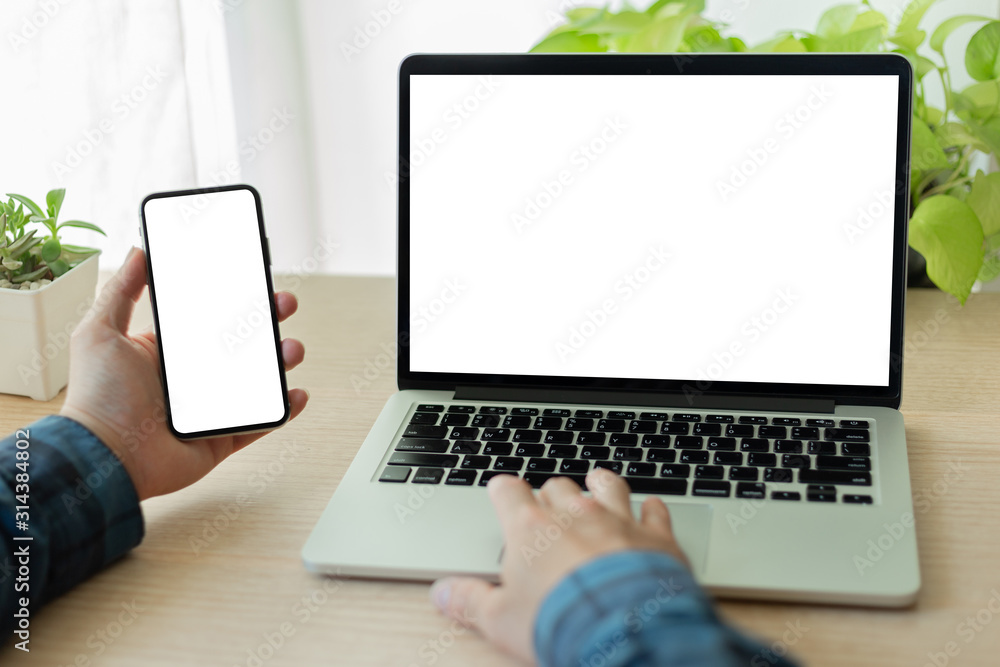 mockup image blank screen computer,cell phone with white background for advertising text,hand man using laptop texting mobile contact business search information on desk in cafe.marketing,design mockup image blank screen computer,cell phone with white background for advertising text,hand man using laptop texting mobile contact business search information on desk in cafe.marketing,design