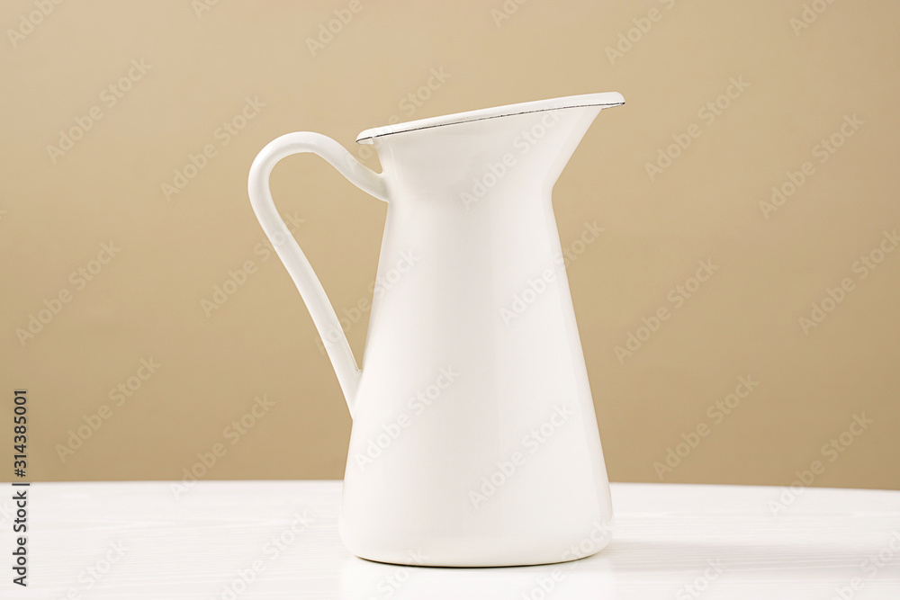 A white vessel placed on a wooden table top in front of a warm background. A white vessel placed on a wooden table top in front of a warm background.