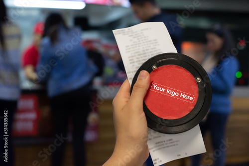 Hand showing Invoice with Wireless calling system restaurant or pager customers system  and person row background.
