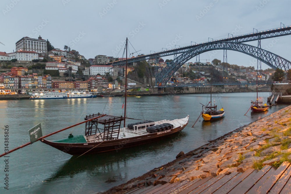 PORTO, PORTUGAL - OCTOBER 18, 2017: Dom Luis bridge over Douro river in Porto, Portugal. Port wine carrier boats on the river.