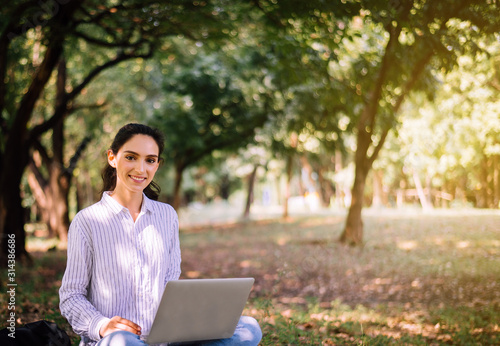 Beautiful young woman using laptop computer at public park in the morning,Happy and smiling,Relaxing time