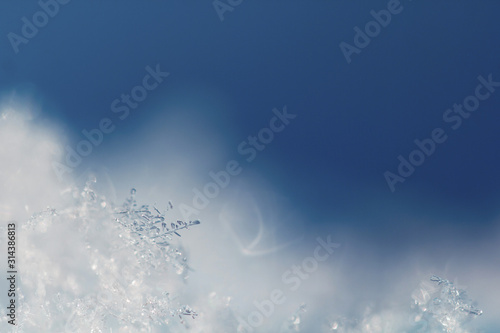 Background from crystal clear real snowflakes in classic blue shades in macro with copy space for your text. Christmas and New Year background frame with a border of natural ice snowflakes close-up.