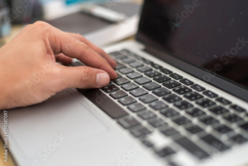 A man is working by using a laptop computer on vintage wooden table. Hands typing on a keyboard. Top view.