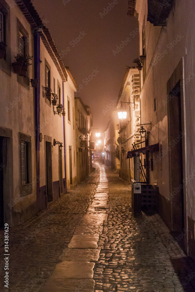 Night view of a narrow cobbled street in Obidos village, Portugal