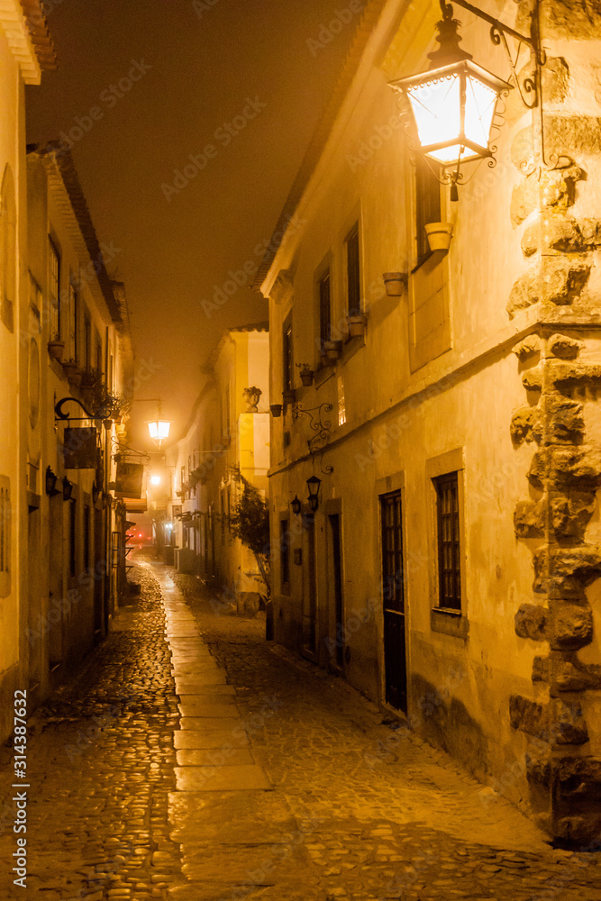 Night view of a narrow cobbled street in Obidos village, Portugal
