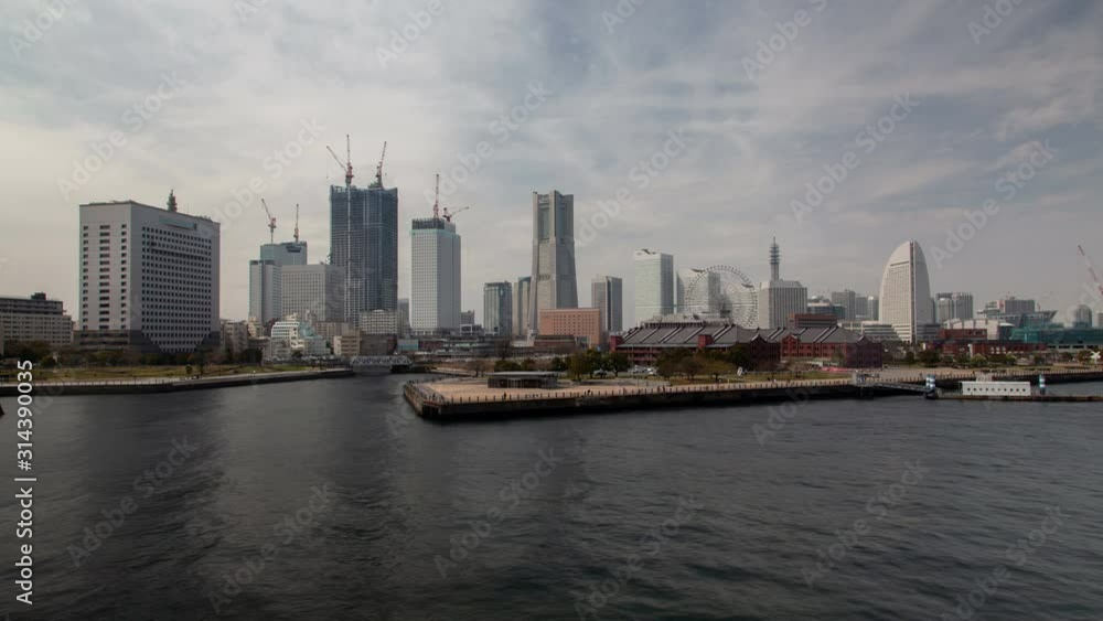 Timelapse Yokohama downtown skyscrapers on waterfront and park with Ferris wheel view from sea bay with sailing motorboats Timelapse Yokohama downtown skyscrapers on waterfront and park with Ferris wheel view from sea bay with sailing motorboats