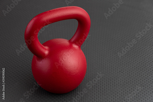 Simple fitness, red kettlebell on a black gym floor