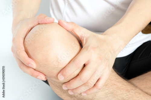Knee pain .man sitting on the bed  Her hand caught at the knee. Having painful feet and stretching muscles fatigue To relieve pain. health concepts.