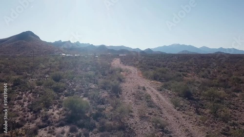 Drone aerial view of a wide dirt trail through the desert near Avra Valley, Arizona, USA with the Santa Rita Mountains in the distance photo