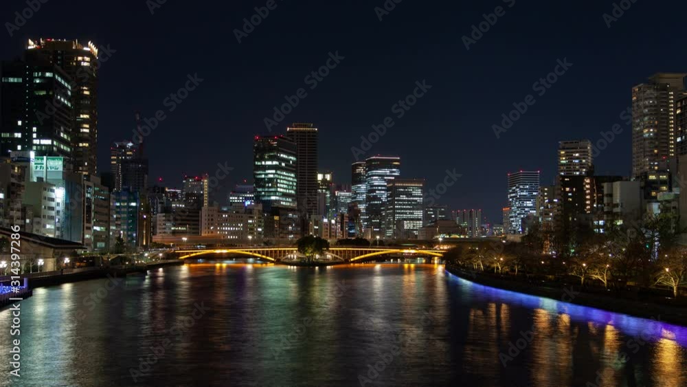 Timelapse Osaka river bridge among skyscrapers apartment buildings with illumination reflected on water and sailing boats at night Timelapse Osaka river bridge among skyscrapers apartment buildings with illumination reflected on water and sailing boats at night