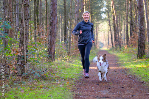 Fototapeta Naklejka Na Ścianę i Meble -  Happy woman full of vitality exercising her dog