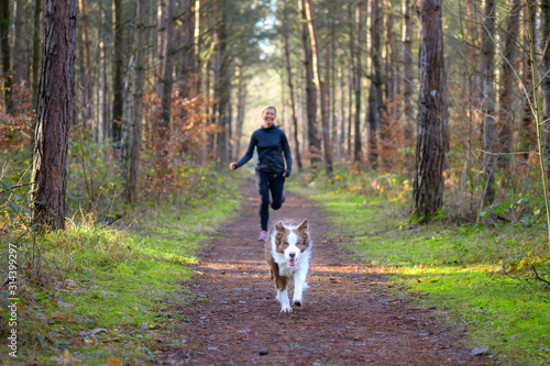 Woman jogging in forest with her dog