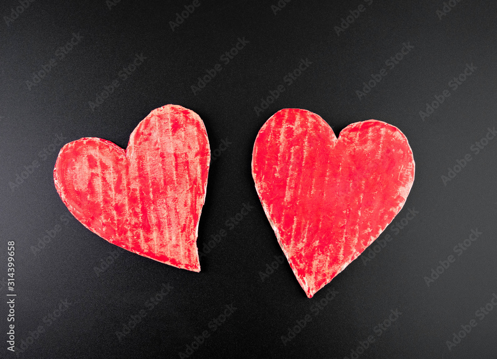 Two red heart-shaped recycled cardboard on dark background. Love symbol for valentines day. Concepts of Love and Romance.