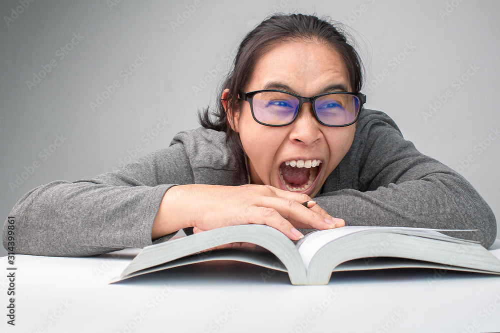 Stressed woman reading a book to exam and yelling on grey background. Stressed woman reading a book to exam and yelling on grey background.