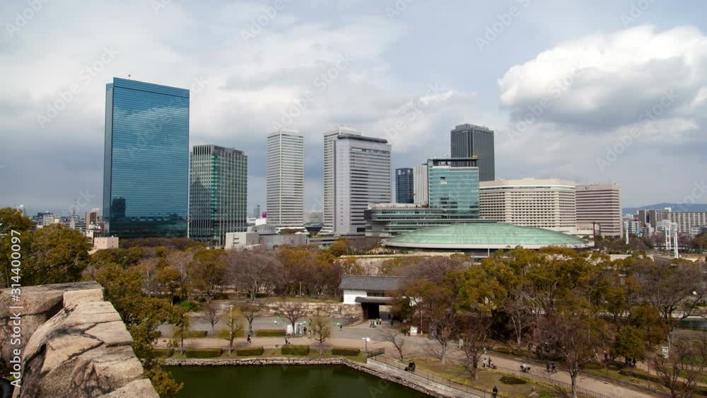 Timelapse Osaka public park with round construction on embankment at downtown skyscrapers under sky with clouds casting shadows Timelapse Osaka public park with round construction on embankment at downtown skyscrapers under sky with clouds casting shadows