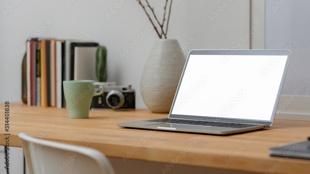 Close up view of workspace with mock-up laptop and office supplies on wooden desk and chair Close up view of workspace with mock-up laptop and office supplies on wooden desk and chair