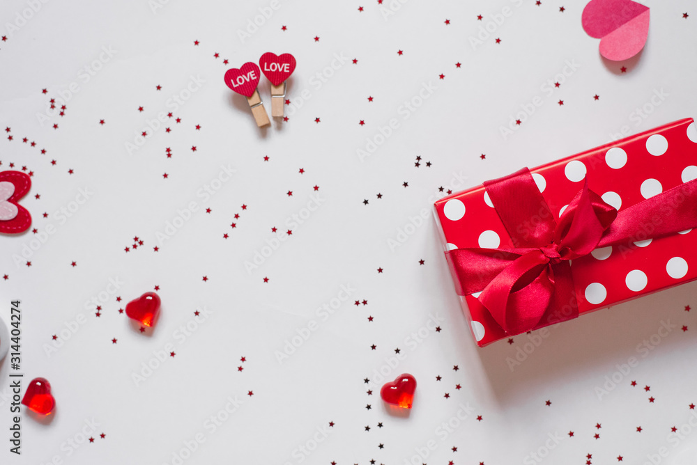 Gift with red bow, confetti, clothespins with hearts and hearts on a white background. The background of Valentine's day. Gift with red bow, confetti, clothespins with hearts and hearts on a white background. The background of Valentine's day.