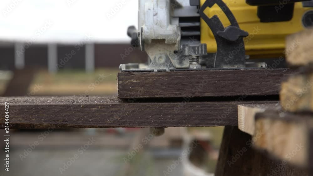 A man is sawing a board. Work with a tree. Saw boards. Build a house. Hand electric saw. Work carpenter. Do it yourself. A man is sawing a board. Work with a tree. Saw boards. Build a house. Hand electric saw. Work carpenter. Do it yourself.