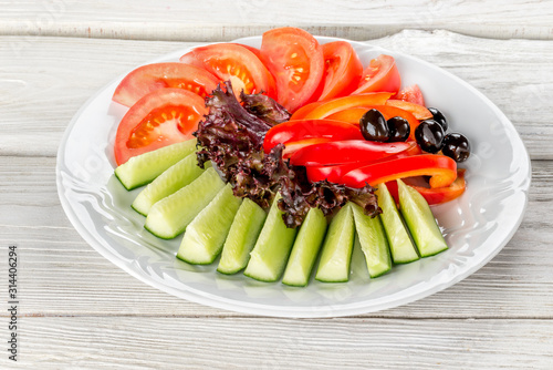 Vegetable white plate with cucumbers, tomatoes, peppers, olives