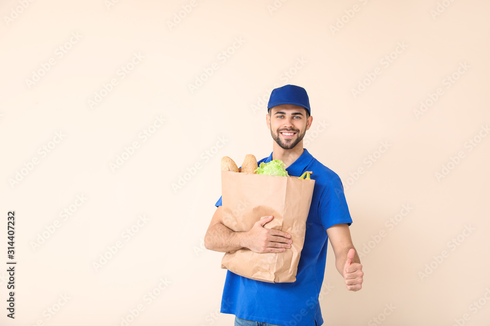 Handsome worker of food delivery service showing thumb-up on color background Handsome worker of food delivery service showing thumb-up on color background