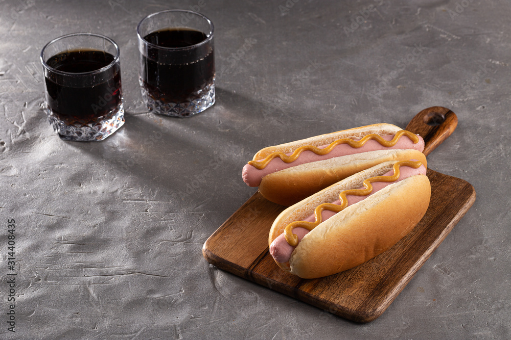 Hot dogs with mustard on a wooden board. Hot dogs served with cola on a  stone table. Free space for text foto de Stock | Adobe Stock