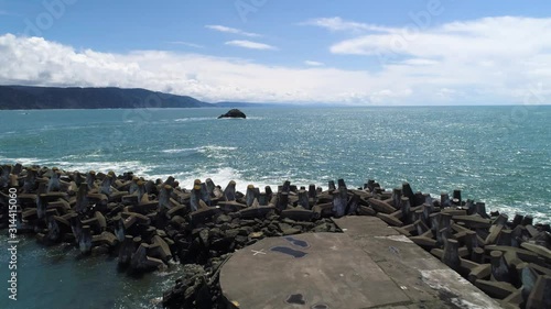 Aerial view of waves crashing into jetty on Pacific Ocean coast on sunny day. photo