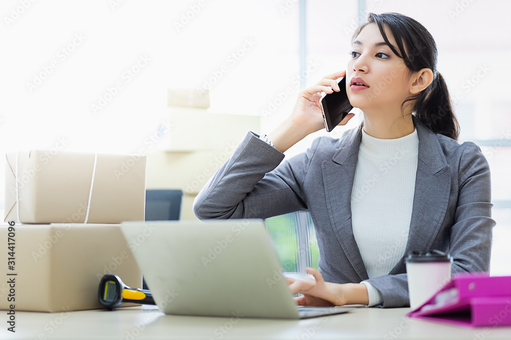 Online shopping SME entrepreneur or freelance working concept. Young asian women working laptop and talking smartphone from customer. Business owner working at home office packaging background. Online shopping SME entrepreneur or freelance working concept. Young asian women working laptop and talking smartphone from customer. Business owner working at home office packaging background.