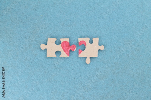 Puzzle with a red heart on the blue felt background. Two disconnected halves. Valentine's day stock photo with empty space for your text. For web, print, postcard, background and wallpaper 