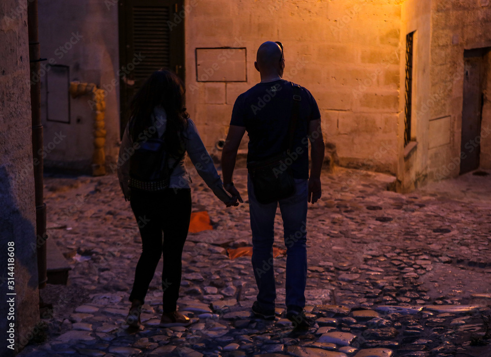 Couple during a walk on Cobblestone street in the Sassi di Matera a historic district in the city of Matera. Basilicata. Italy