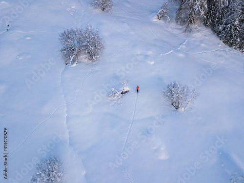 Aerial view of mountaineer hiking upwards with touring ski in snow covered backcountry. Concept of backcountry skiing.