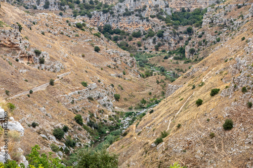 View of Gravina river canyon and park of the Rupestrian Churches of Matera with houses in caves di Murgia Timone near ancient town Matera (Sassi), , Basilicata, Italy