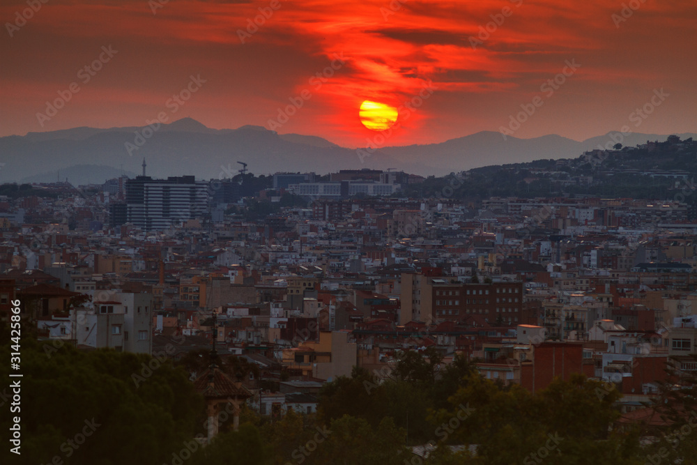 view of the city of Barcelona, capital of province of Catalonia Spain at sunset in summer in front of mountains with red salt and residential buildings in shade