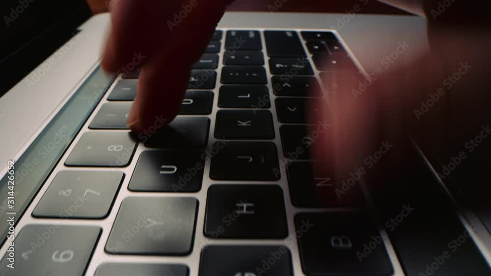 Low angle shot moving across laptop computer keyboard as woman types quickly 4K