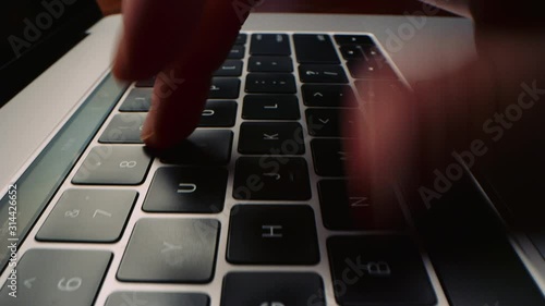 Low angle shot moving across laptop computer keyboard as woman types quickly 4K