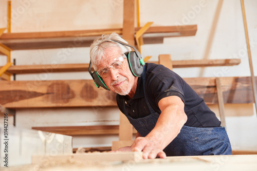 Senior Mann als Schreiner sägt Holz