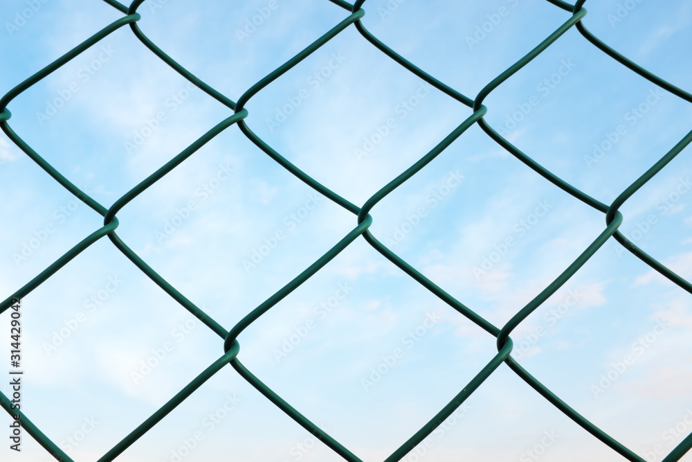 Chainlink wire fence against a morning blue sky for prison and security concept Chainlink wire fence against a morning blue sky for prison and security concept