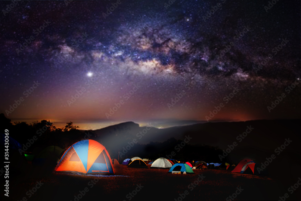 Camping and tent under the with forest near in the mountains . A tent pitched up and glowing under the milky way