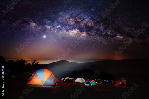 Camping and tent under the with forest near in the mountains . A tent pitched up and glowing under the milky way