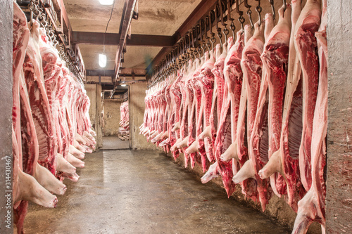 A lot of chopped fresh raw pork meat hanging and arrange and processing deposit in a refrigerator, in a meat factory.