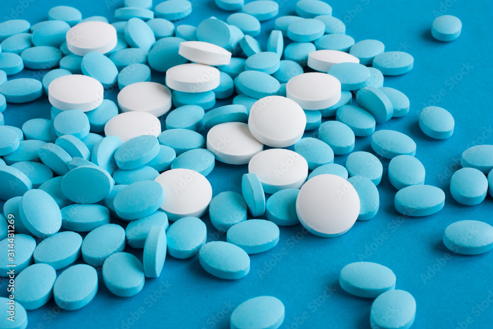 White and light blue pills on a blue background. Medicine and health