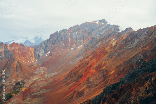Vivid multicolor landscape to big rocky mountain ridge. Giant highland rough wall close-up. Red orange yellow rocks and stones. Beautiful scenery of colorful rockies. Multi-colored mountain range.