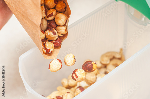 Pour hazelnuts in one bowl with cashew nuts to create an assortment of nuts for a balanced diet. photo