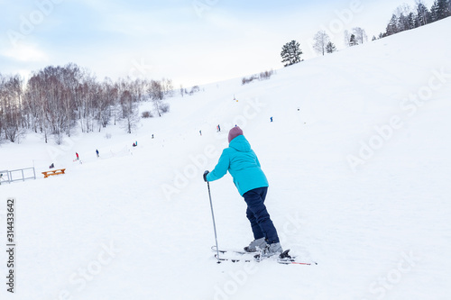 A woman skier slides down the Altai mountain over white snow in a sports tourist base Turquoise Katun. Seasonal sports.