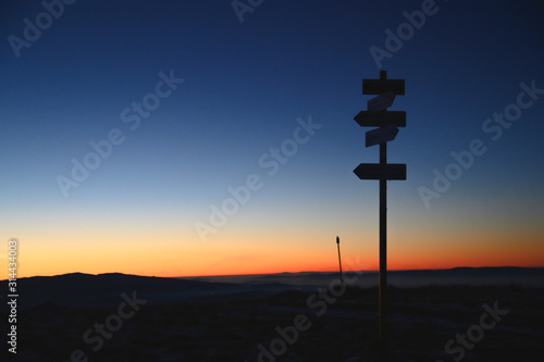 Silhouette of arrows in mountains, sunrise light in background. Arrows showing right direction